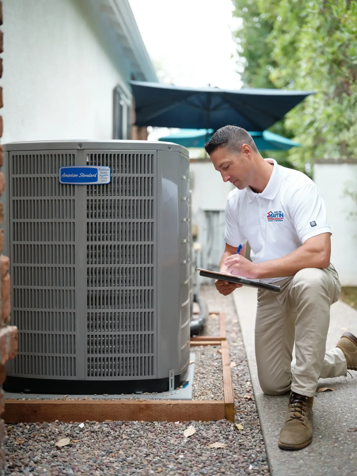 HVAC technician recording readings beside a residential outdoor air conditioning unit