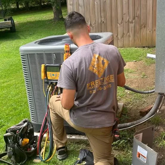 Technician performing a maintenance check using gauges beside an outdoor HVAC unit
